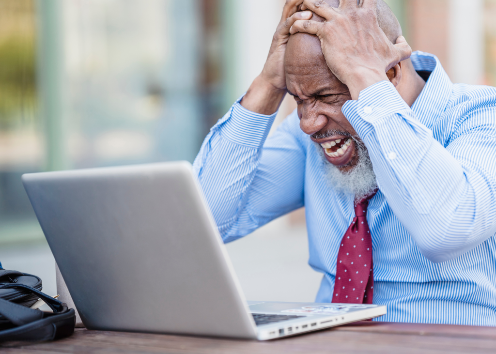 Frustrated man with furrowed brows looking at a computer screen, symbolizing challenges with online renewal due to registration holds.